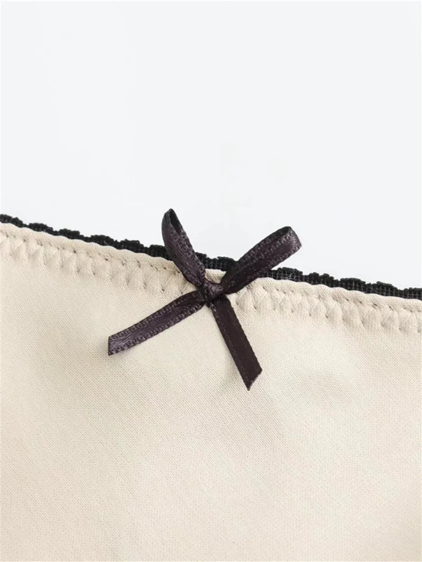 Beige fabric with a black lace trim and bow on a white background