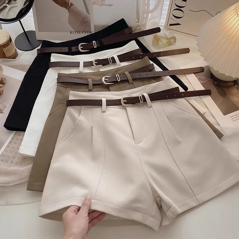 Beige shorts with multiple belts on a surface