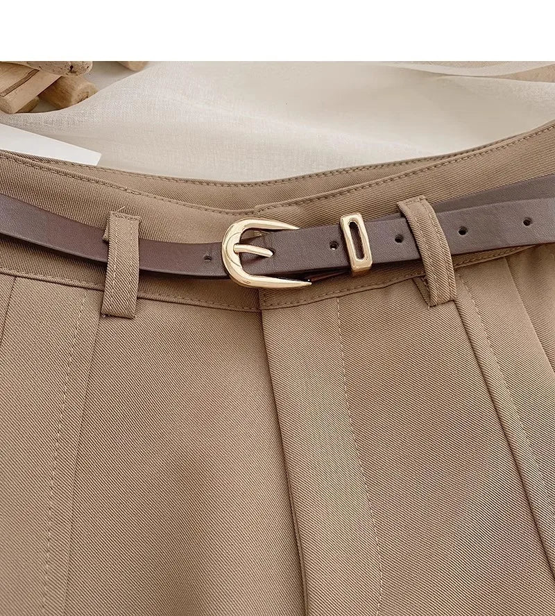 Close-up of beige pants with a brown belt and gold buckle.