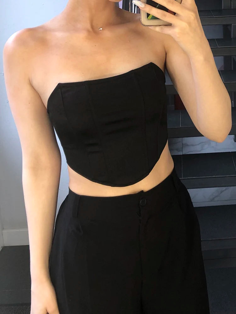 Person wearing a black strapless top and black pants in front of a mirror.