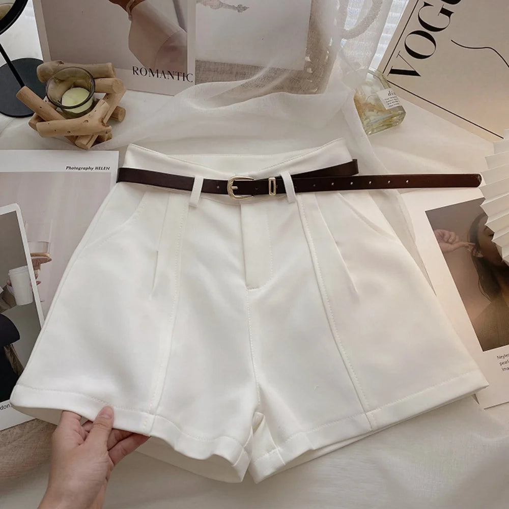 White shorts with a brown belt held by a hand on a magazine background