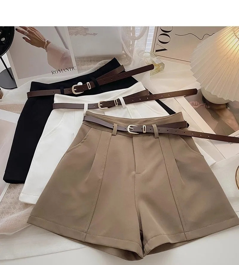 Beige shorts with brown belts on a surface with magazines underneath