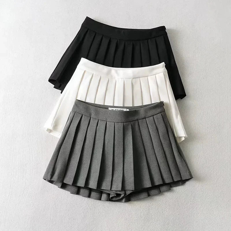Three pleated skirts in black, white, and gray on a light gray background