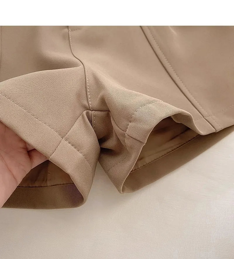 Close-up of beige fabric with a hand holding it, on a light beige background