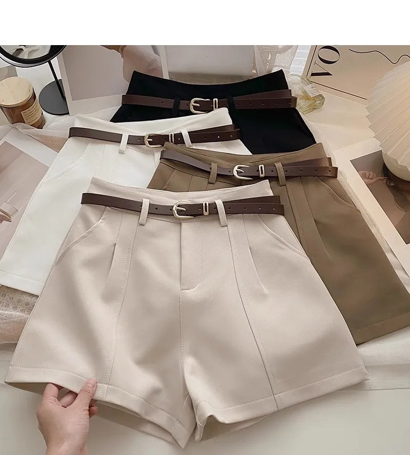 Beige shorts with brown belts on a surface with magazines.