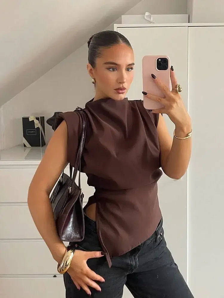 Woman taking a mirror selfie wearing a brown top and black pants in a room.