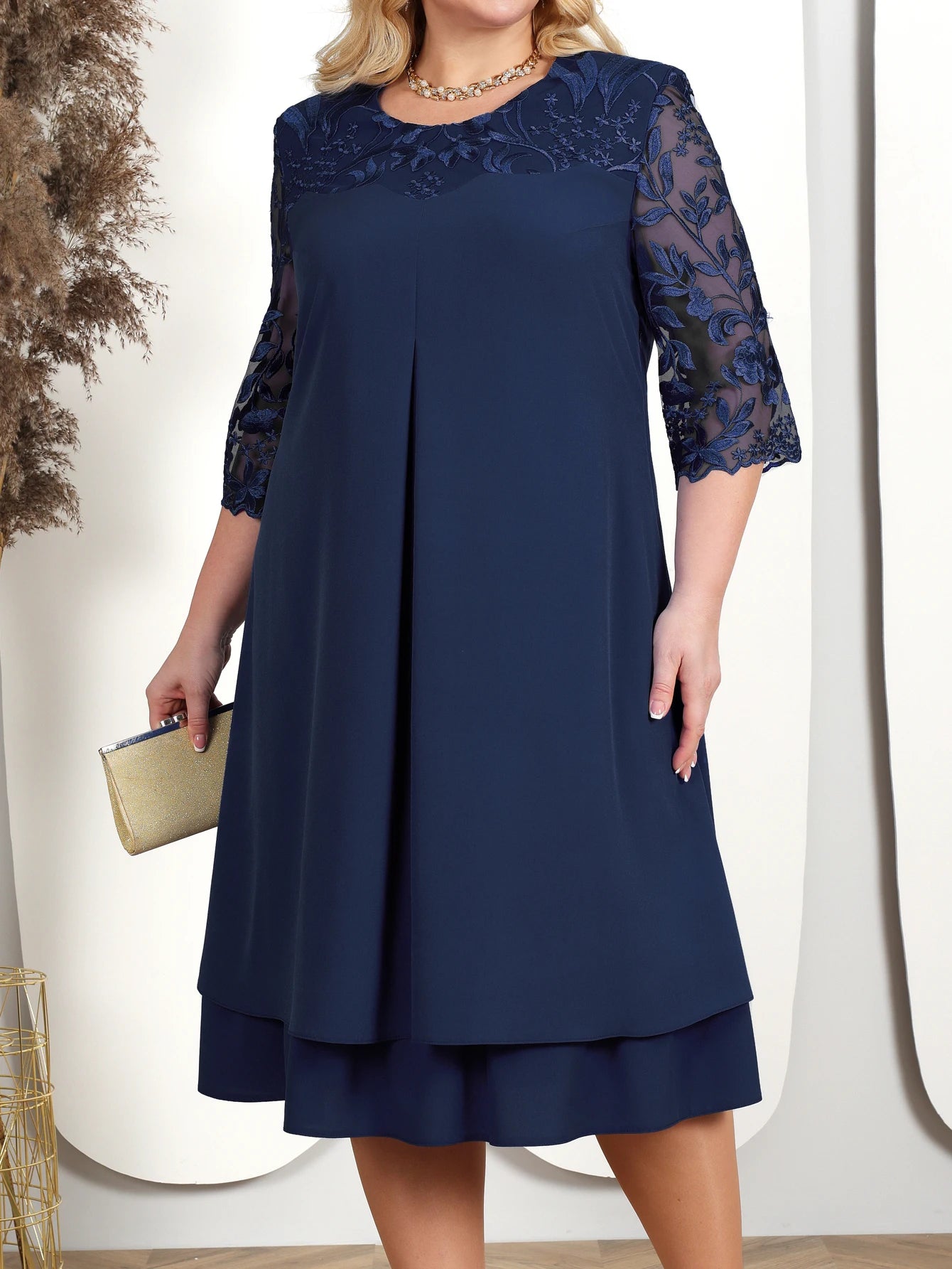 Woman wearing a navy blue dress with lace details on a white background