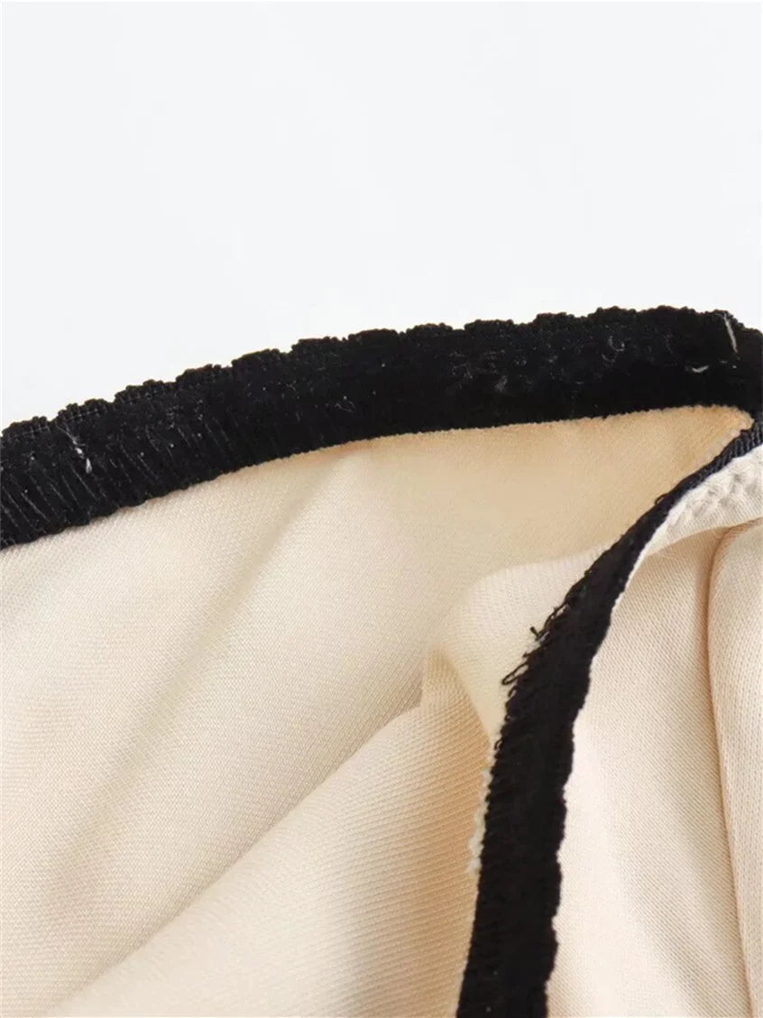 Close-up of beige fabric with black trim on a white background