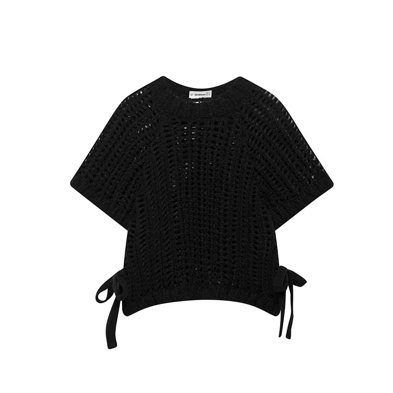 Black knit poncho with tie details on a white background