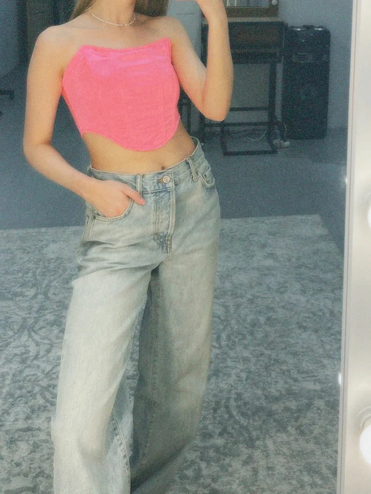 Person wearing a pink strapless top and light blue jeans in front of a mirror.