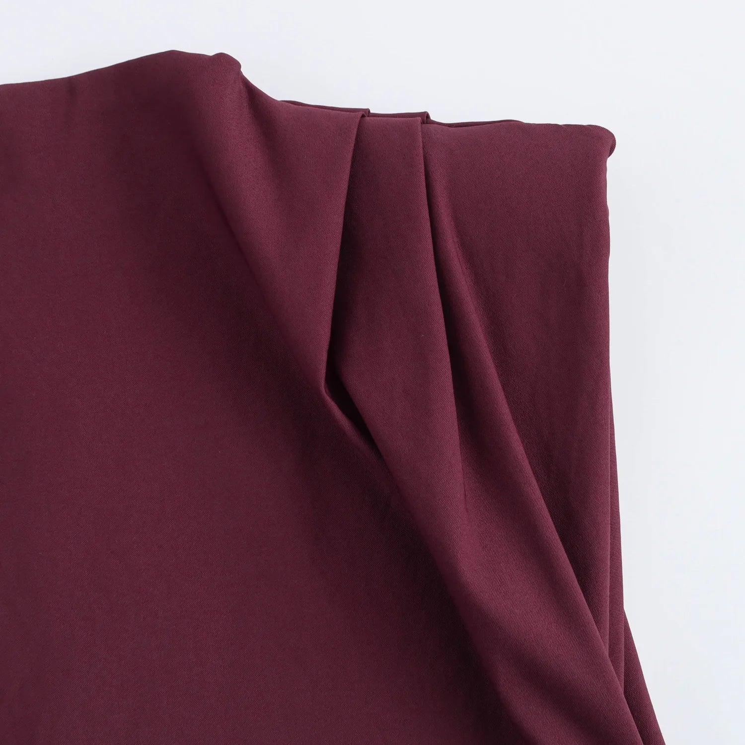 Close-up of maroon fabric with folds on a light gray background