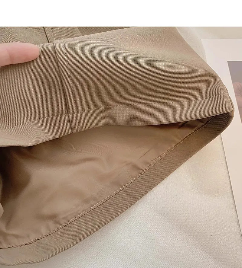 Close-up of beige fabric with a hand touching it on a light background