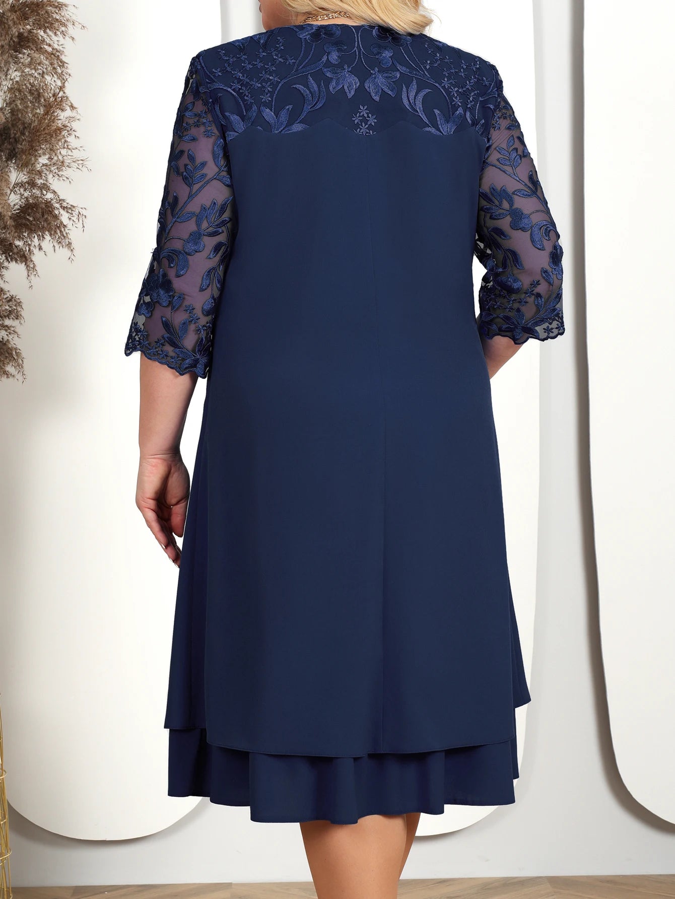 Navy blue dress with lace detailing on sleeves against a white background