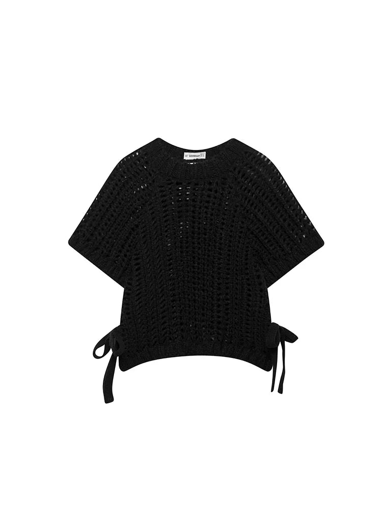Black knit poncho with tie details on a white background