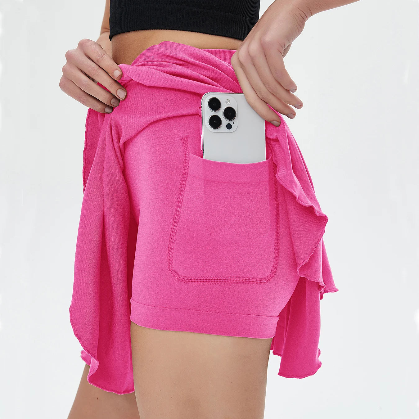 Person wearing a bright pink skirt with a pocket, holding a phone.