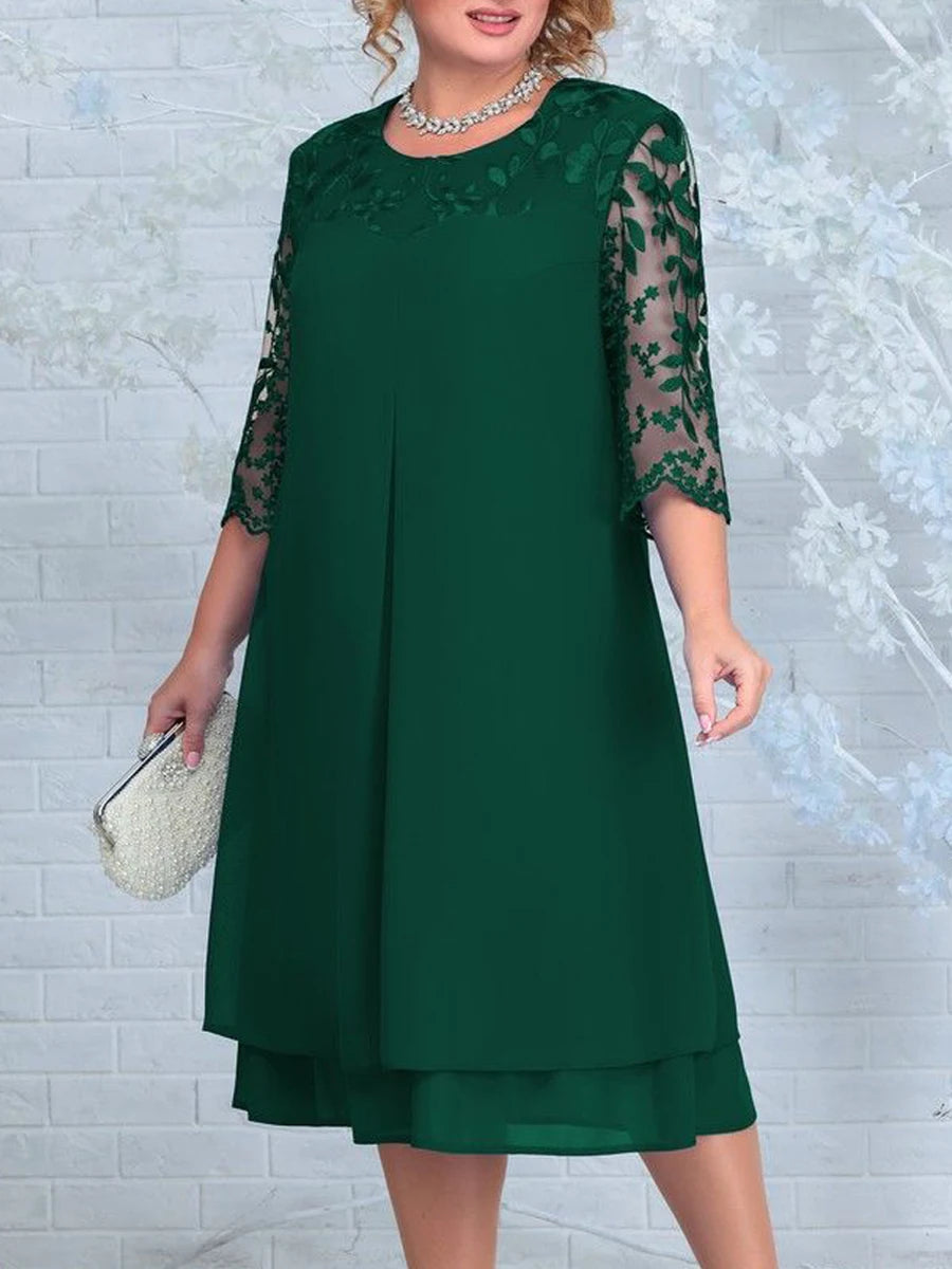 Woman wearing a green dress with lace sleeves against a light gray background