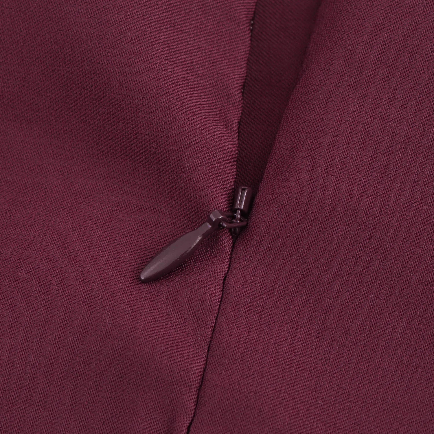 Close-up of a zipper on a maroon fabric background