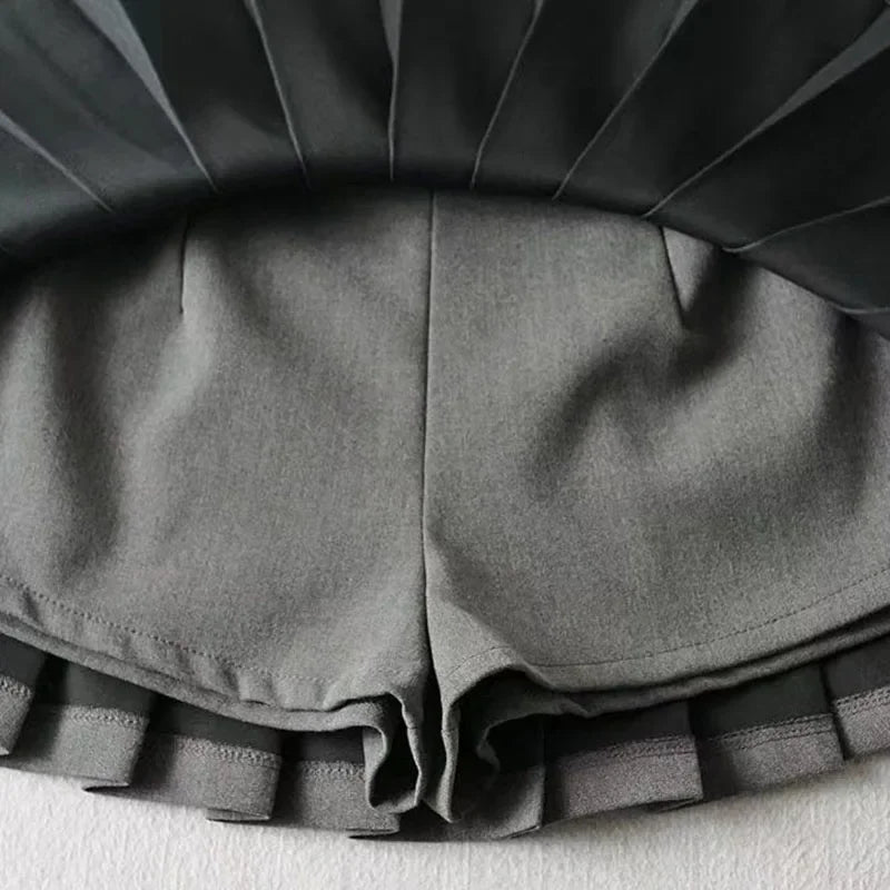 Close-up of gray shorts with pleated details on a light background