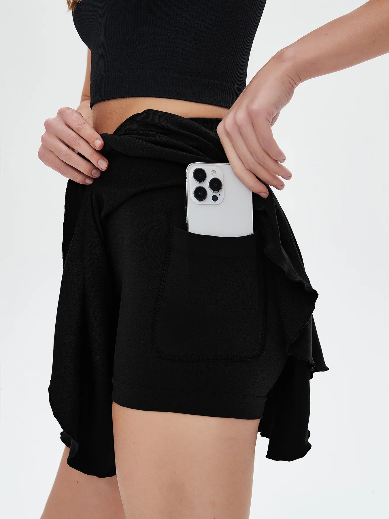 Person wearing a black outfit with a phone in a pocket on a white background - RemarkStore