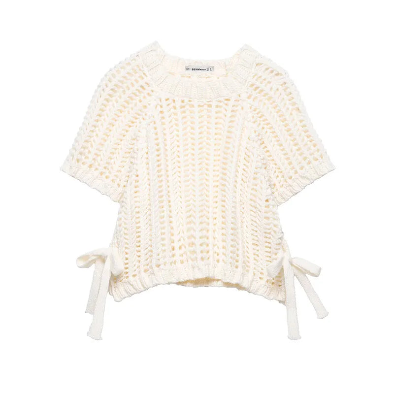 White knitted baby outfit with tassels on a white background