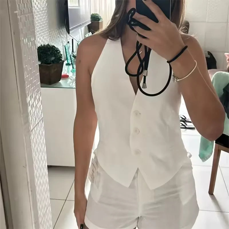 Person wearing a white sleeveless top and shorts in an indoor setting.